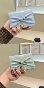 Détail de portefeuilles nœud bleu clair et vert menthe avec charms dorés et cuir poli
