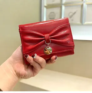 Gros plan d'un portefeuille en cuir verni rouge avec grand nœud et pendentif en métal