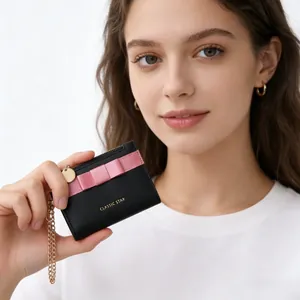 Macro detail of black leather wallet featuring a pink bow and classic star branding