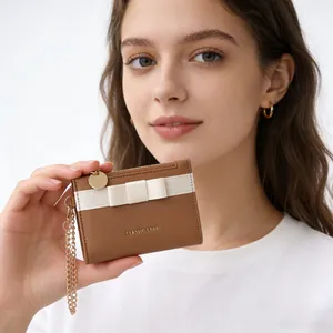 Detailed view of brown leather wallet with white bow and golden chain strap