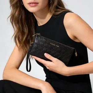 Close-up of black woven leather wristlet featuring a gold logo and premium metal zipper