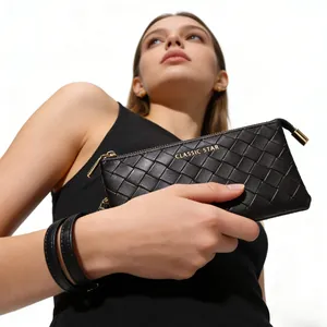 Detail of black woven leather texture and gold metal zipper on a stylish clutch bag