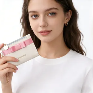 Detail view of cream macaron wallet featuring a pink bow and golden zipper puller