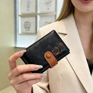 Close-up of black textured trifold wallet featuring a cute cat illustration held by a model