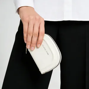 Dettaglio del portamonete bianco a semicerchio in pelle con zip e logo a stella