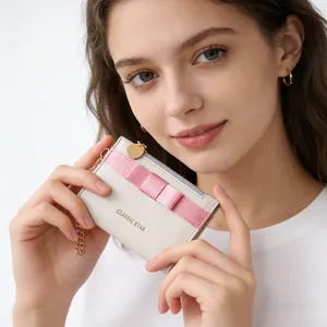 Close-up of a beige zip wallet featuring a pink ribbon bow and gold Classic Star text