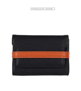 Detail of pebbled leather card holder featuring black texture and orange stripe accent