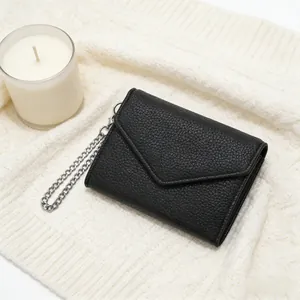 Close-up of black lychee grain leather wallet with silver chain on white sweater background
