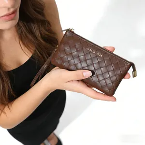 Detail of dark brown woven leather clutch featuring a gold zipper and wrist strap