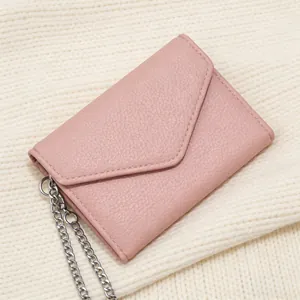Detail of light pink lychee pattern leather wallet on white knit fabric background