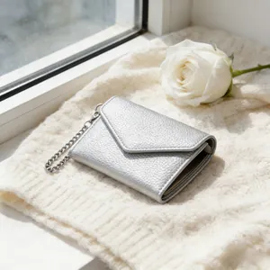 Silver lychee grain mini envelope wallet with metal chain on white knit background