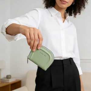 Dettaglio del portamonete a semicerchio verde chiaro in pelle sintetica con logo argento