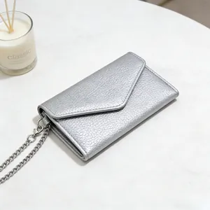 Silver litchi texture envelope wallet with metal chain on a marble background