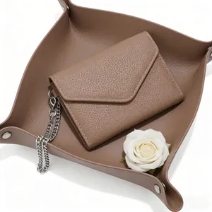 Detail of brown lychee pattern leather envelope wallet with silver chain and white rose