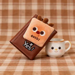 Detail of a brown tri-fold wallet featuring a plush cartoon character and Good embroidery