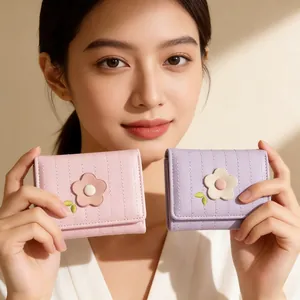 Détail de portefeuilles en cuir rose et violet avec pétales 3D et broderie de feuilles vertes