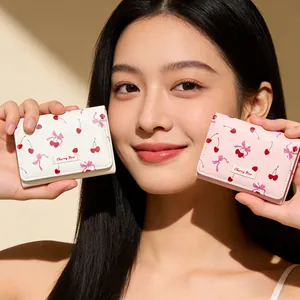 Close-up of compact cherry and bow print tri-fold wallets held by a model