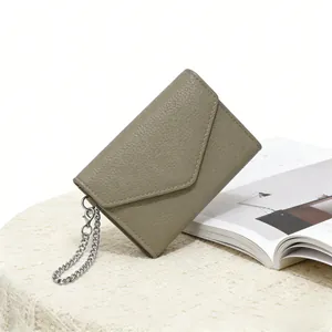Detail of grey-green litchi grain small wallet with silver chain on knitted fabric