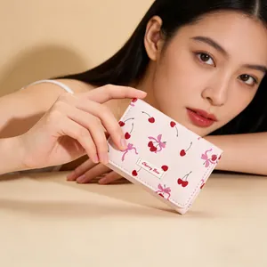 Close-up of pink cherry and bow print wallet with Cherry Bow brand label in hand