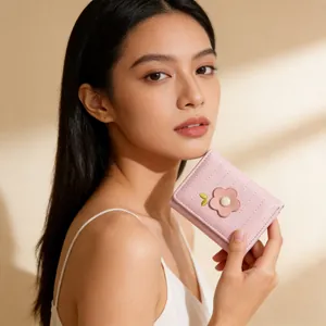 Gros plan d'un petit portefeuille rose en cuir synthétique avec broderie florale