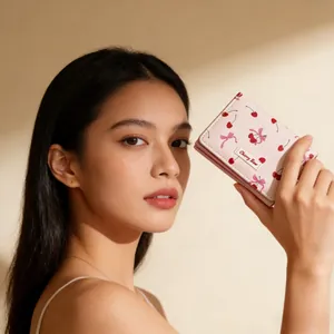 Detail of pink three-fold wallet featuring cherry bow print and stitched label held by model