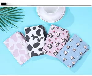 Flat lay of multiple cow print PU leather coin purses with zippers and strawberry patterns