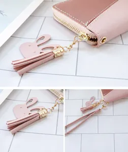 Détail du portefeuille en similicuir rose avec fermeture éclair dorée et breloque lapin