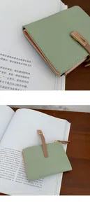 Macro detail of a light green PU leather bifold wallet with brown strap and zipper closure