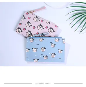 Detail view of pink and blue cow print coin purses with zipper and wrist straps