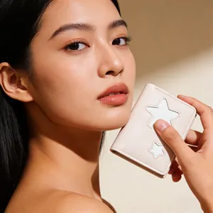 Close-up of a pink star pattern leather wallet held by a model in warm light