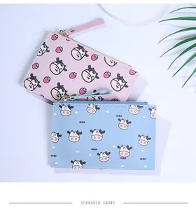 Close-up of cute cow print coin purses in pink and blue PU leather with zipper pulls