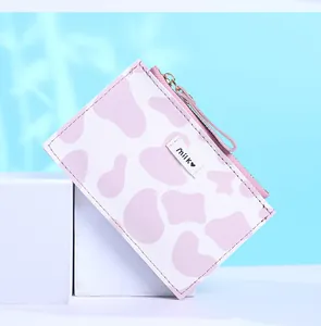Close-up of pink cow print small wallet featuring a zipper closure and a milk label