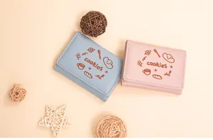 Détail de la broderie de motifs de biscuits sur des portefeuilles pliants en cuir