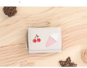 Close-up of cream tri-fold wallet with cherry and ice cream embroidery on wooden base