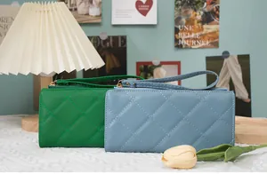 Detailed close-up of quilted long wallets in green and light blue with wrist straps