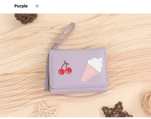 Detail view of purple tri-fold wallet with cherry and ice cream embroidery and zip