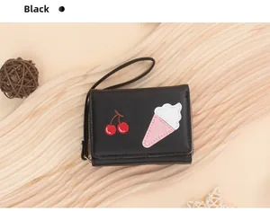Detail of a small black embroidered wallet with cherry and ice cream cone patterns