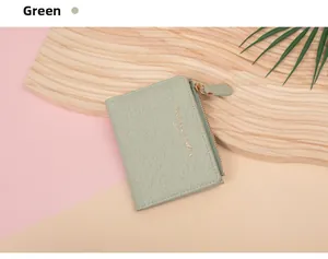 Close-up of green crocodile texture wallet with gold zipper and embossed letters