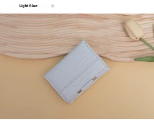 Detail der hellblauen dreifaltigen Brieftasche mit Krokoprägung und Goldverzierung auf Holz