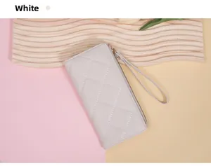 Detail of white quilted long wallet with zipper and wristlet on decorative tray