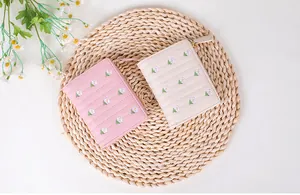 Détails de broderies florales sur de petits portefeuilles zippés en rose et crème