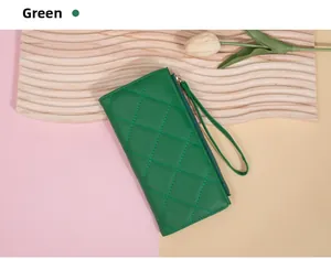 Detail of green quilted long wallet with wristlet and zipper closure on a soft background