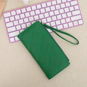 Green quilted leather long zipper wallet for women with wristlet on purple keyboard