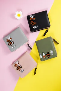 Flat lay of small wallets in four colors featuring cute animal embroidery and metal zippers