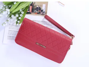 Détail d'un long portefeuille rouge matelassé avec logo doré et dragonne amovible pour femme