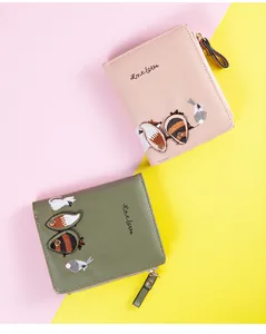 Detail view of pink and green embroidered wallets with fox and rabbit leather motifs