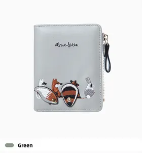 Detail of green faux leather wallet featuring cute forest animal embroidery and zipper