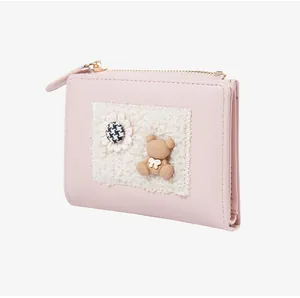 Close-up of pink leather wallet featuring a 3D teddy bear and houndstooth floral detail