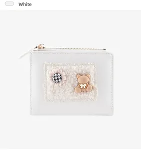 Detail of white leather coin purse featuring a plush bear and plaid flower applique