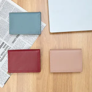 Three compact minimalist pebble grain leather wallets for women on a wooden background
